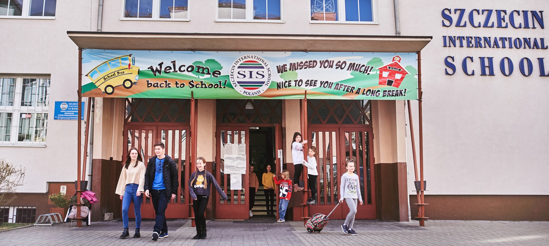 Uczniowie przed wejściem do Szczecin International School z banerem powitalnym